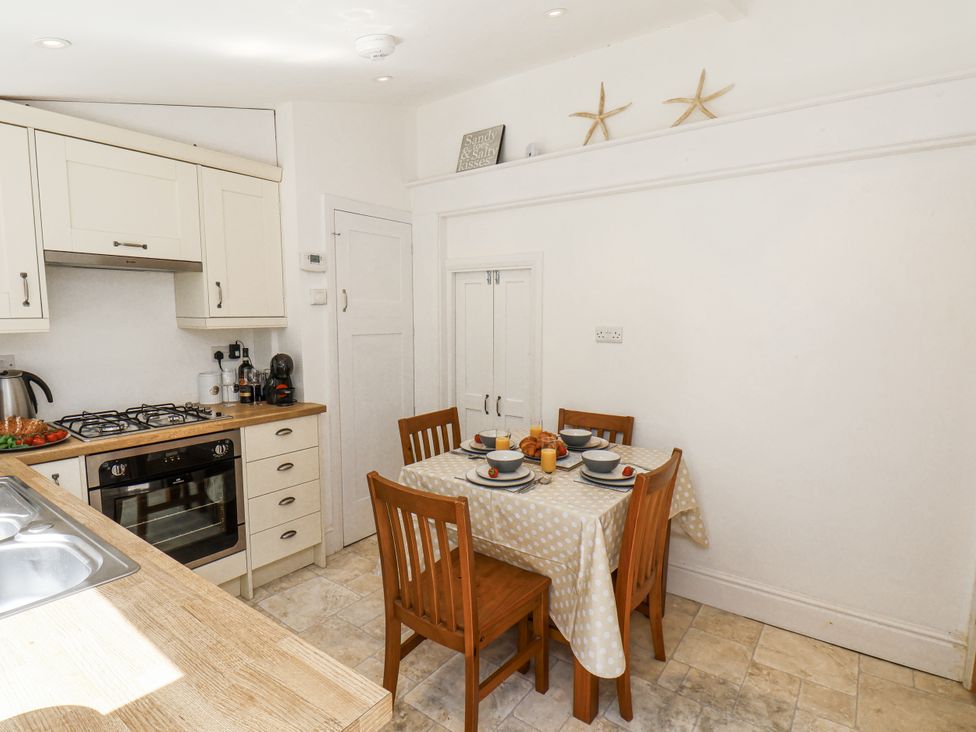 A kitchen with dining table and chairs at Rigg Cottage Sandsend