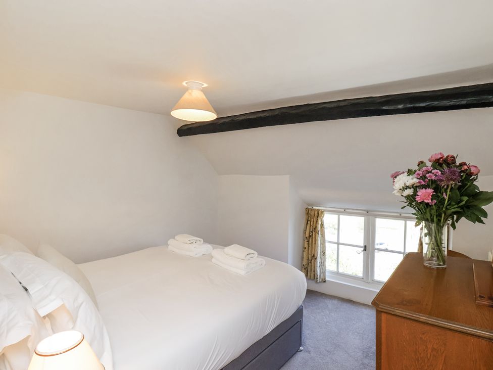 A bedroom with bed, dresser and flowers at Rigg Cottage in Sandsend