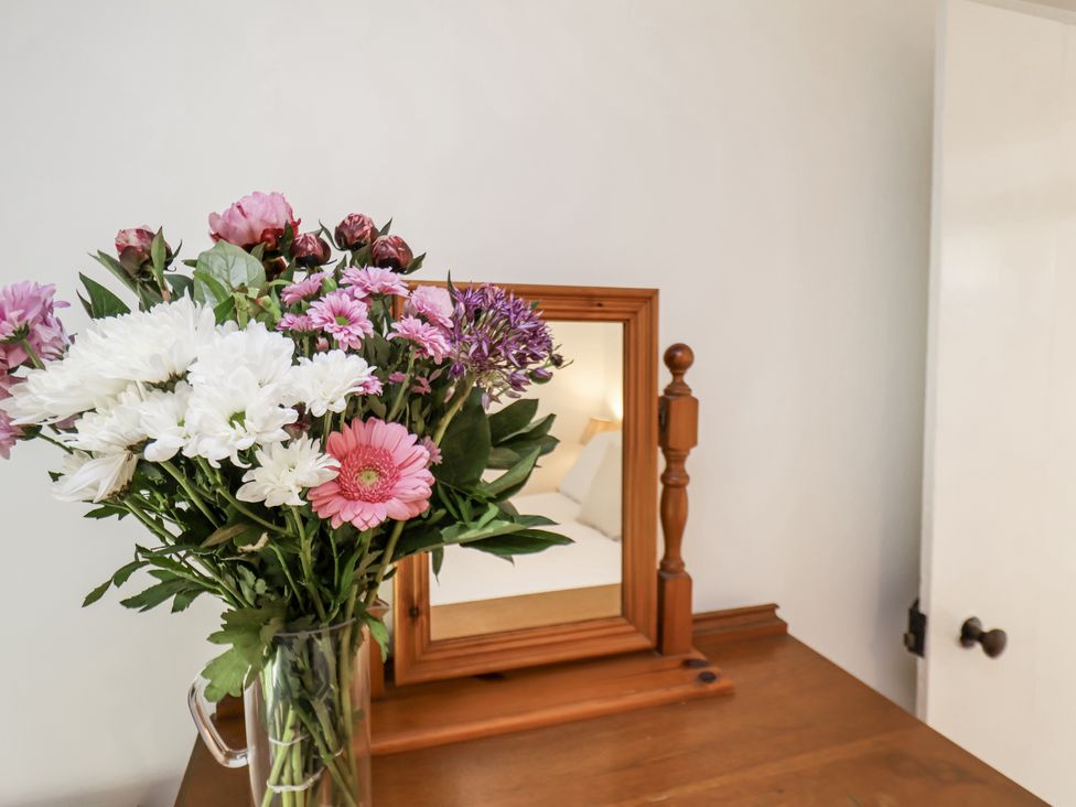 A bouquet of flowers and a mirror on a table at Rigg Cottage in Sandsend