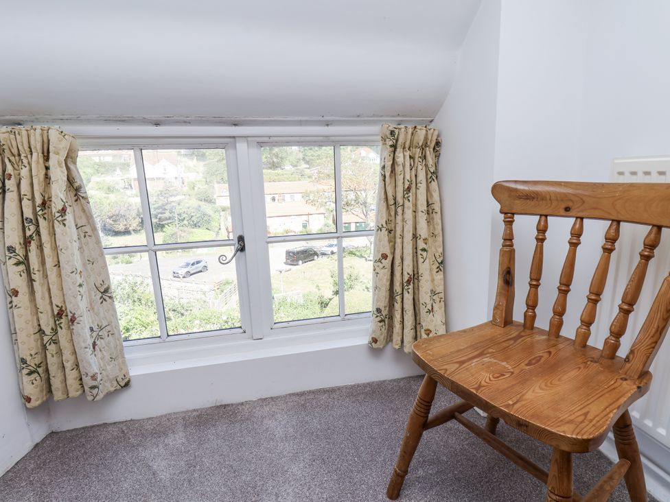 A loft space with a window and a wooden chair at Rigg Cottage Sandsend