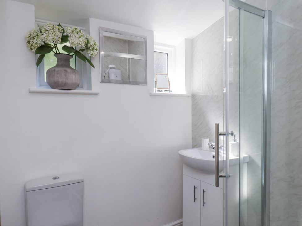 A bathroom featuring a shower, sink, toilet, and window at Rigg Cottage in Sandsend