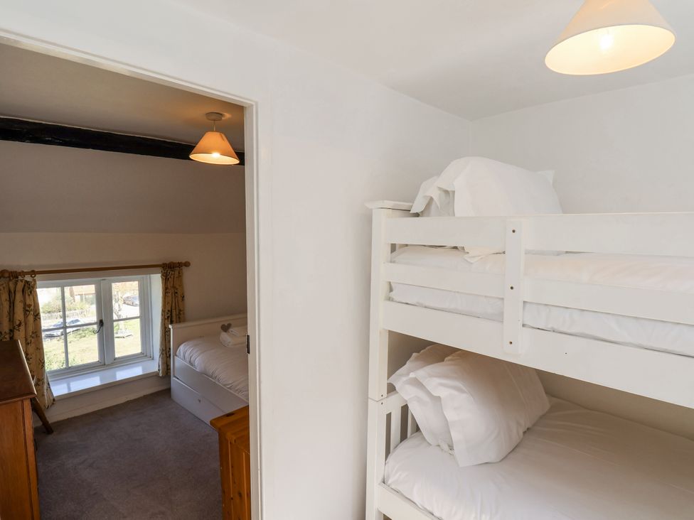 A bedroom with a bunk bed and a single bed at Rigg Cottage in Sandsend