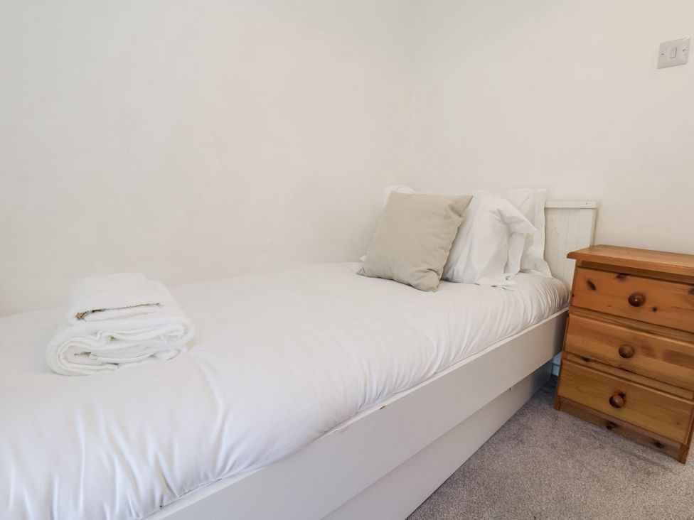 A bed with pillows and towels in a bedroom at Rigg Cottage in Sandsend