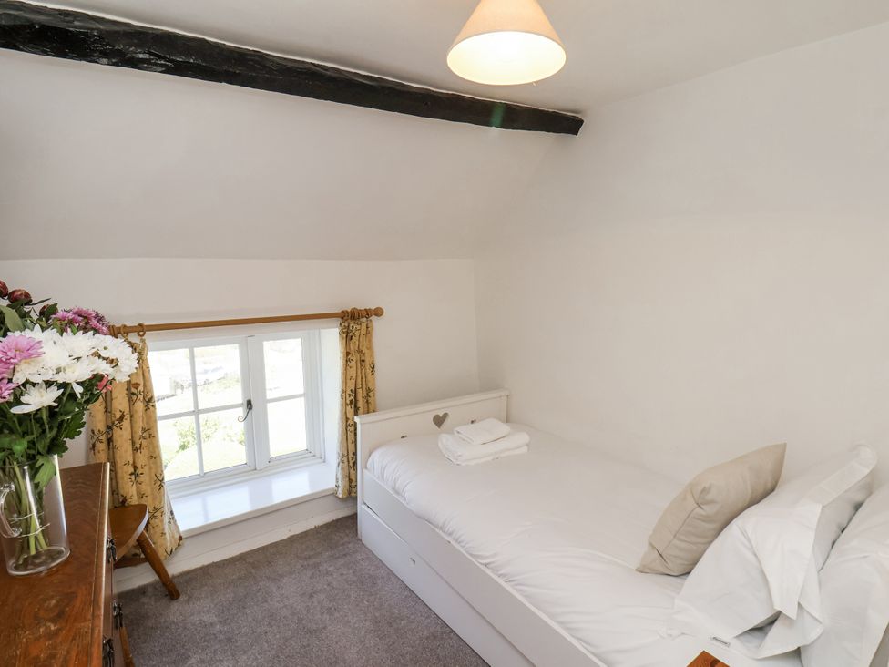 A bedroom with a bed and flowers on a dresser at Rigg Cottage in Sandsend