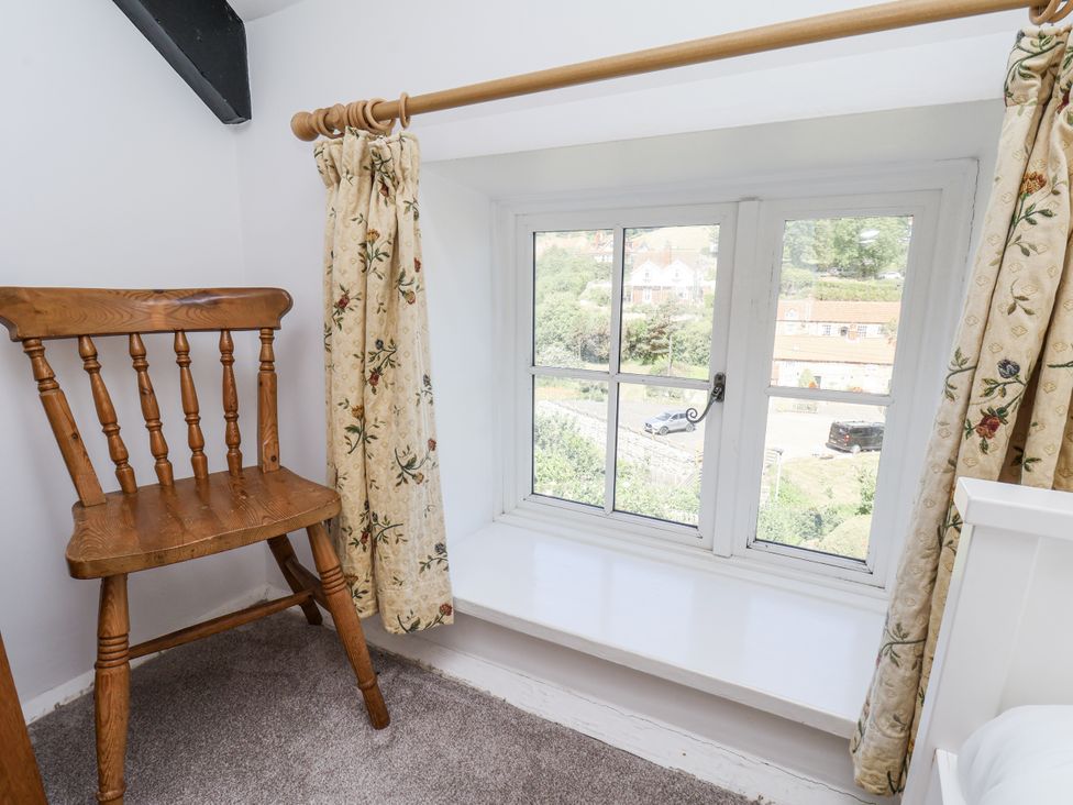 A bedroom with a wooden chair and window at Rigg Cottage Sandsend