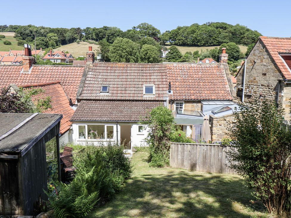 A garden view with rooftops and trees at Rigg Cottage Sandsend