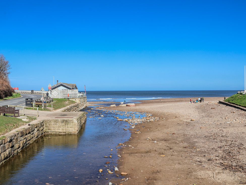 A beach with a stream and benches next to the sea at Rigg Cottage, Mount Pleasant, Sandsend