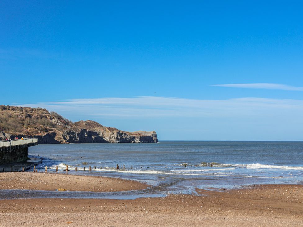 A beach with a pier and cliffs at Rigg Cottage, Mount Pleasant Sandsend