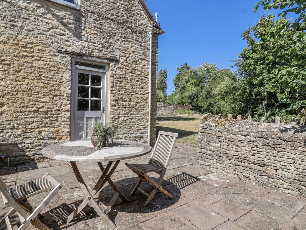 An outdoor patio with a table and chairs at Stable cottage in Sopworth near Sherston