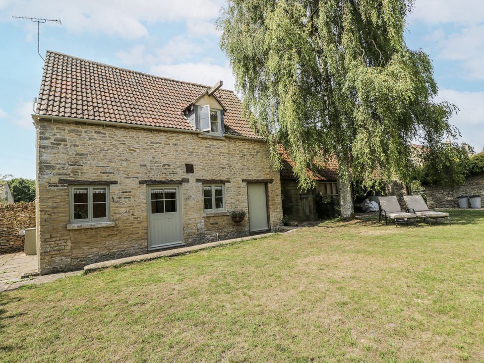 A stone house with windows and a door in the garden at Stable cottage Sopworth near Sherston