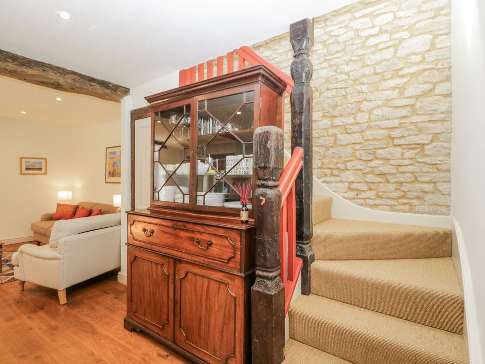 A living room with a wooden cabinet and staircase at Stable cottage Sopworth near Sherston