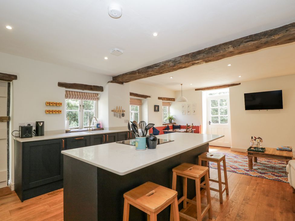 A kitchen with a kitchen island and bar stools at Stable cottage Sopworth near Sherston
