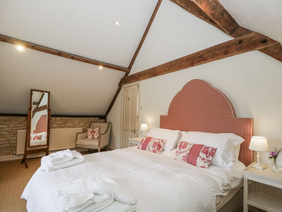A bedroom with a bed and armchair at Stable cottage in Sopworth near Sherston