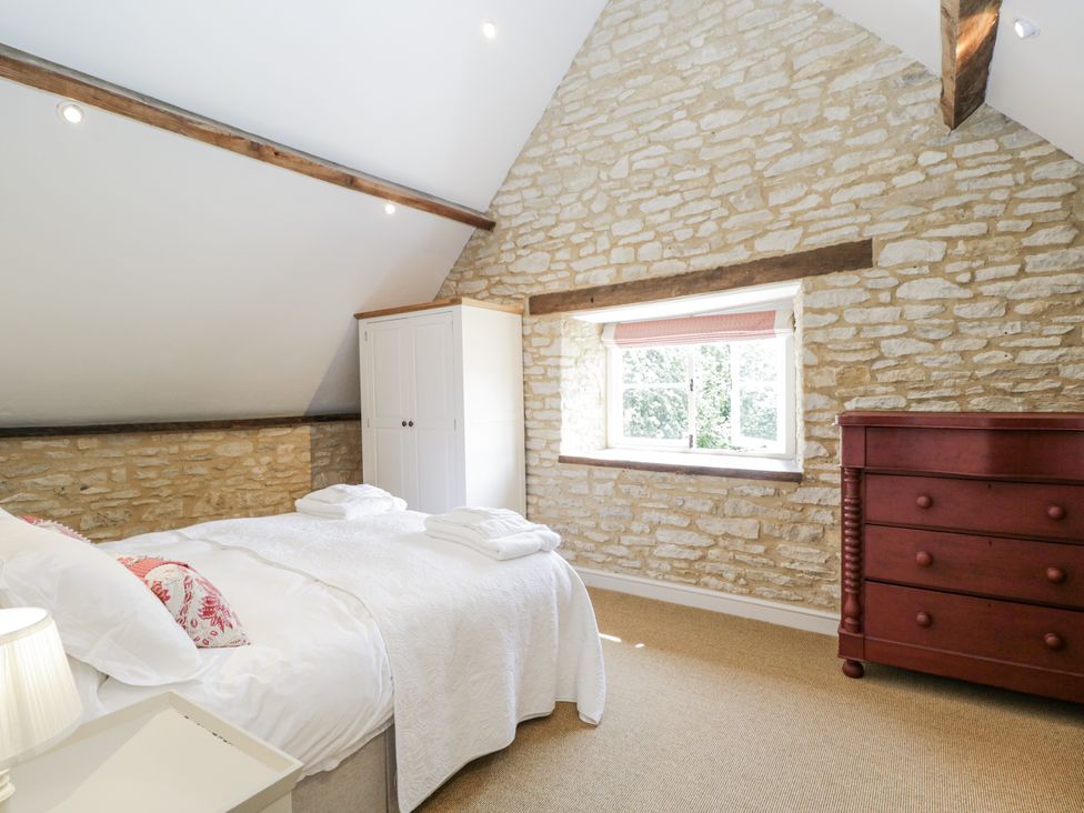 A bedroom with a bed and a wardrobe at Stable cottage Sopworth near Sherston