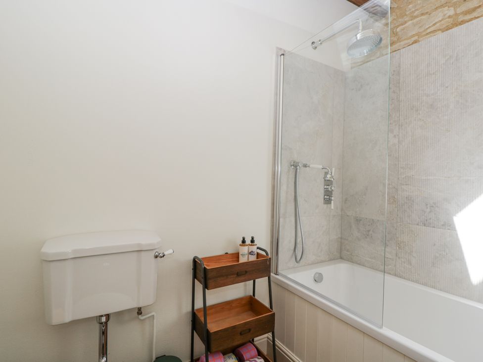 A bathroom with a bathtub and wall-mounted shower at Stable cottage in Sopworth near Sherston