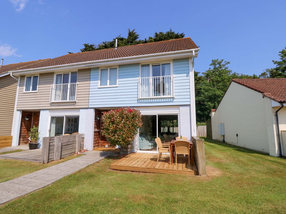 A two-story semi-detached house with patio chairs and table on a wooden deck in the garden at Whitfield P1 in Yarmouth