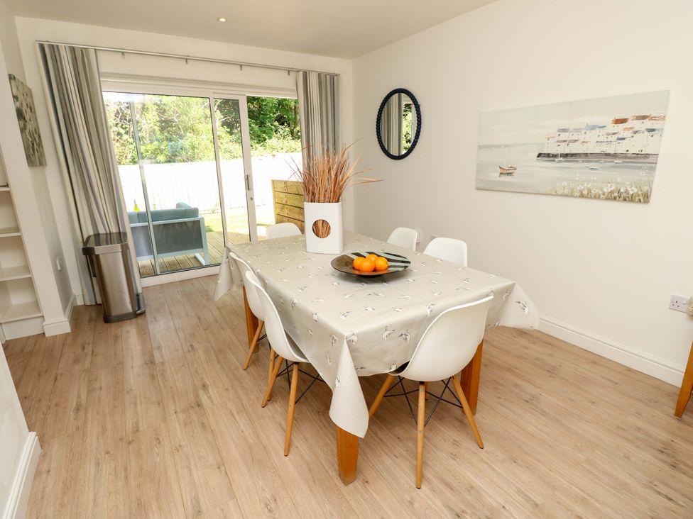 A dining room with a table covered with a tablecloth surrounded by six chairs and sliding glass doors leading to a patio at Whitfield P1 in Yarmouth