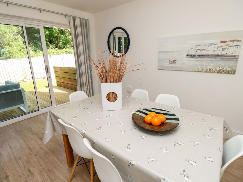 A dining area with a table covered by a patterned cloth chairs around it and a vase with dried plants on top at Whitfield P1 in Yarmouth