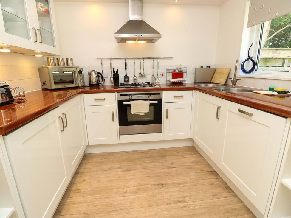 A kitchen with white cabinets wooden countertops a gas stove oven a toaster microwave kettle utensils and a double sink at Whitfield P1 in Yarmouth