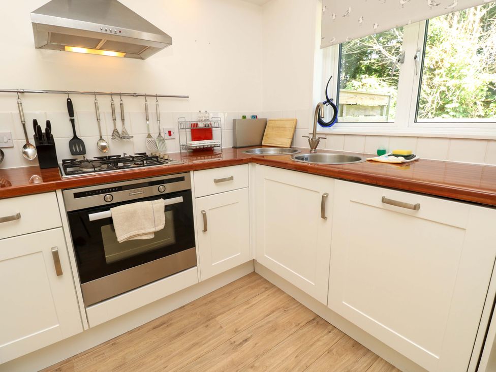 A kitchen with a gas stove oven white cabinets wooden countertop and two round sinks below a window at Whitfield P1 in Yarmouth