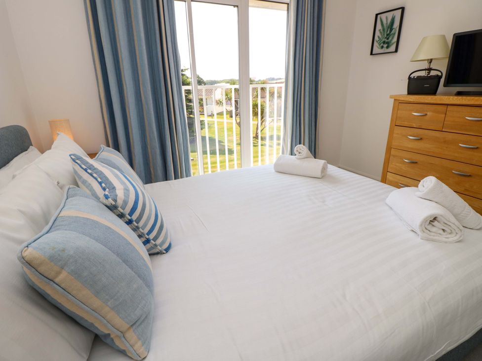 A bedroom with a bed with striped pillows and folded towels with a window and wooden dresser at Whitfield P1 in Yarmouth
