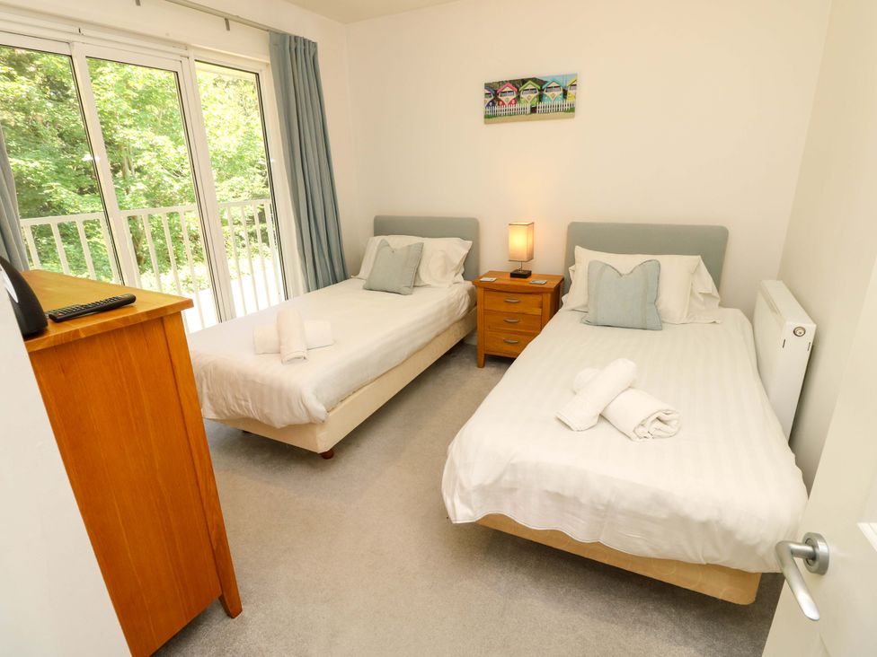 A bedroom with two single beds a wooden dresser and a nightstand with a lamp at Whitfield P1 in Yarmouth