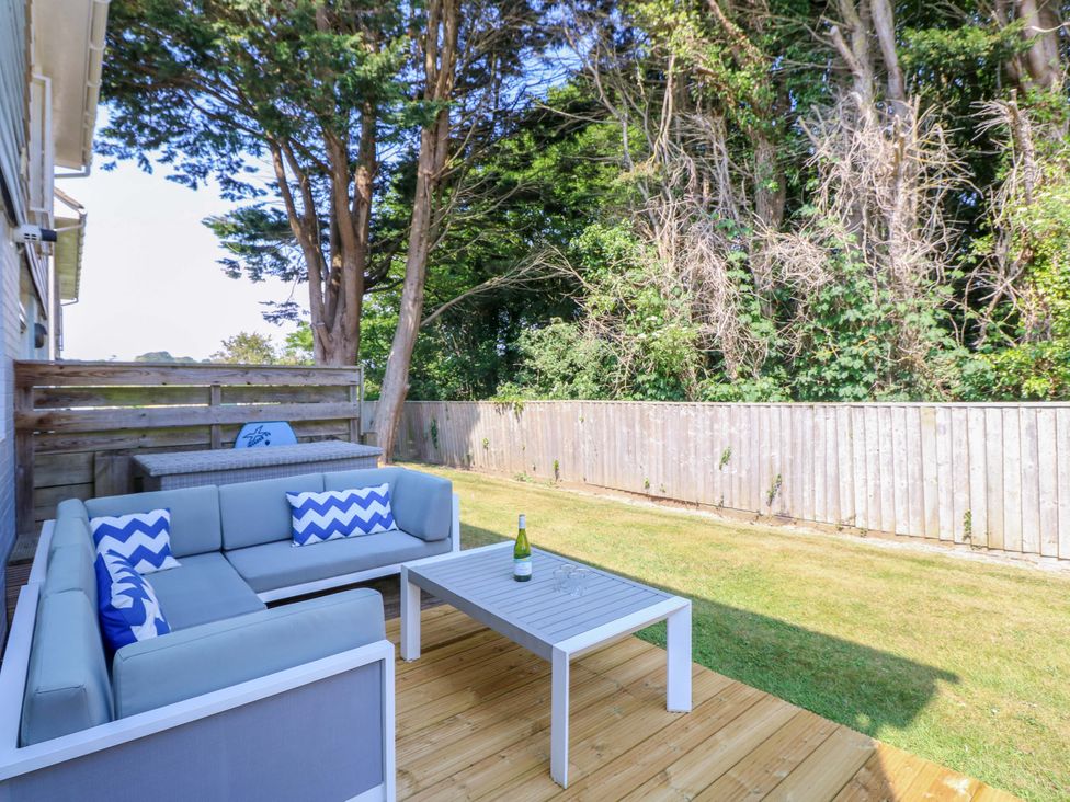 An outdoor patio with a gray sectional sofa and a table with a bottle and glasses on it at Whitfield P1 in Yarmouth