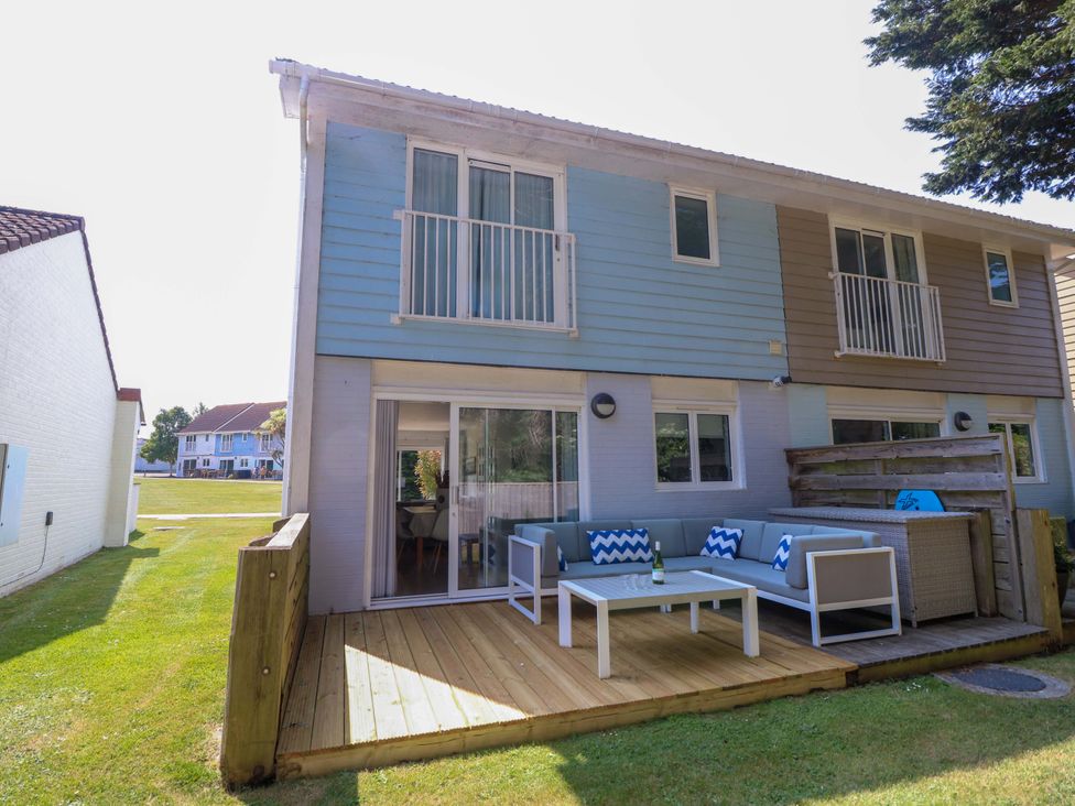 A backyard patio with outdoor seating and a table attached to a two-story house at Whitfield P1 in Yarmouth