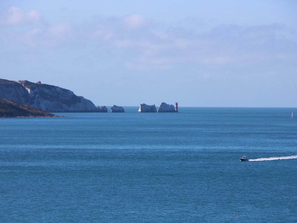 A seascape with cliffs rocks a lighthouse and boats at Whitfield P1 in Yarmouth