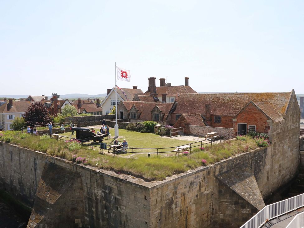 A historic stone fort with grass and flowers on top with people walking and sitting on benches in Yarmouth