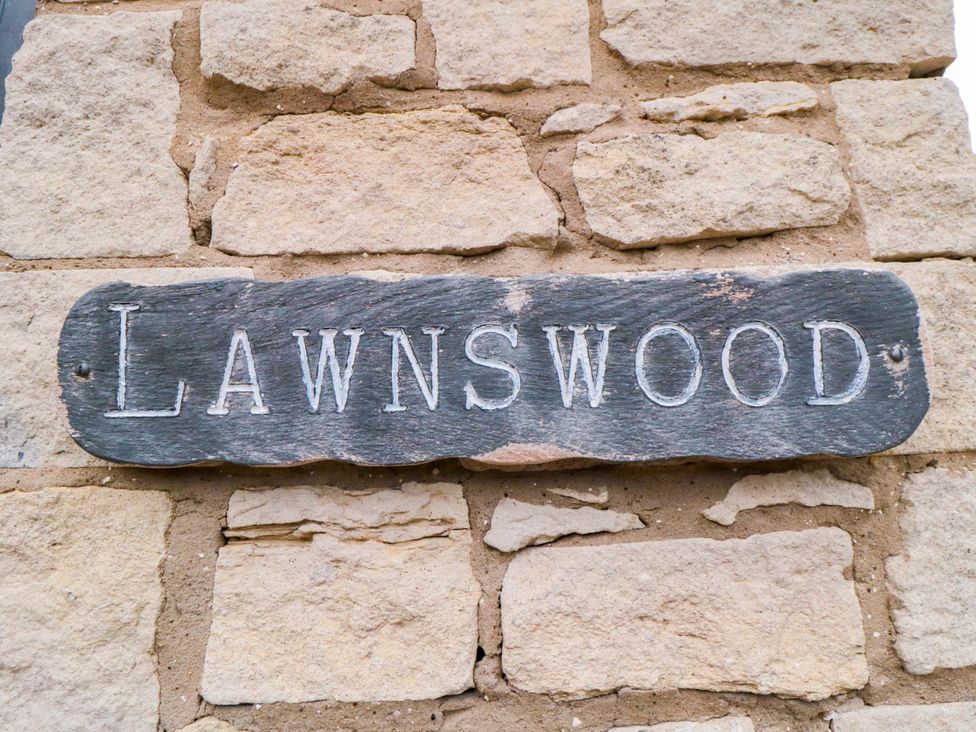 A sign that reads Lawnwood against a stone wall
