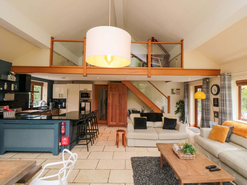 A living room with a kitchen area and staircase at Lawnswood 