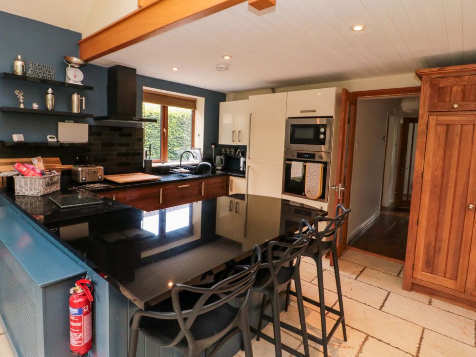 A kitchen with an island, cooking appliances, and bar stools at Lawnswood