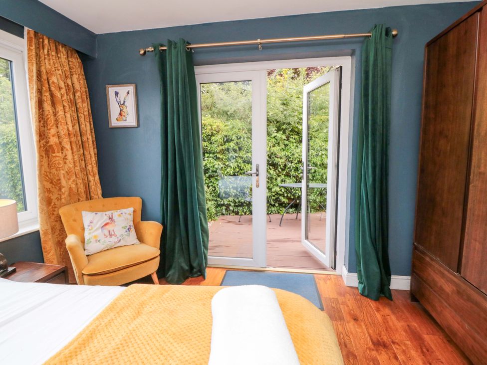 A bedroom with a chair and window leading to patio at Lawnswood