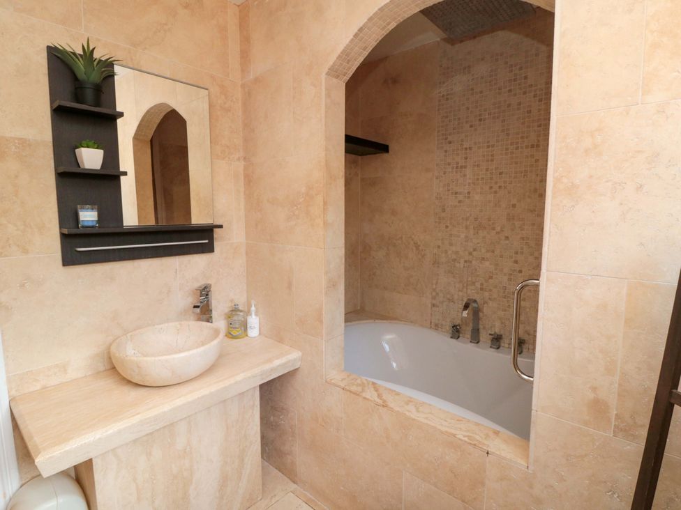 A bathroom with a bathtub and wash basin at Lawnswood