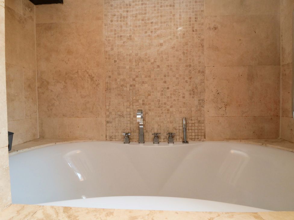 A bathtub with faucets and wall tiles at Lawnswood