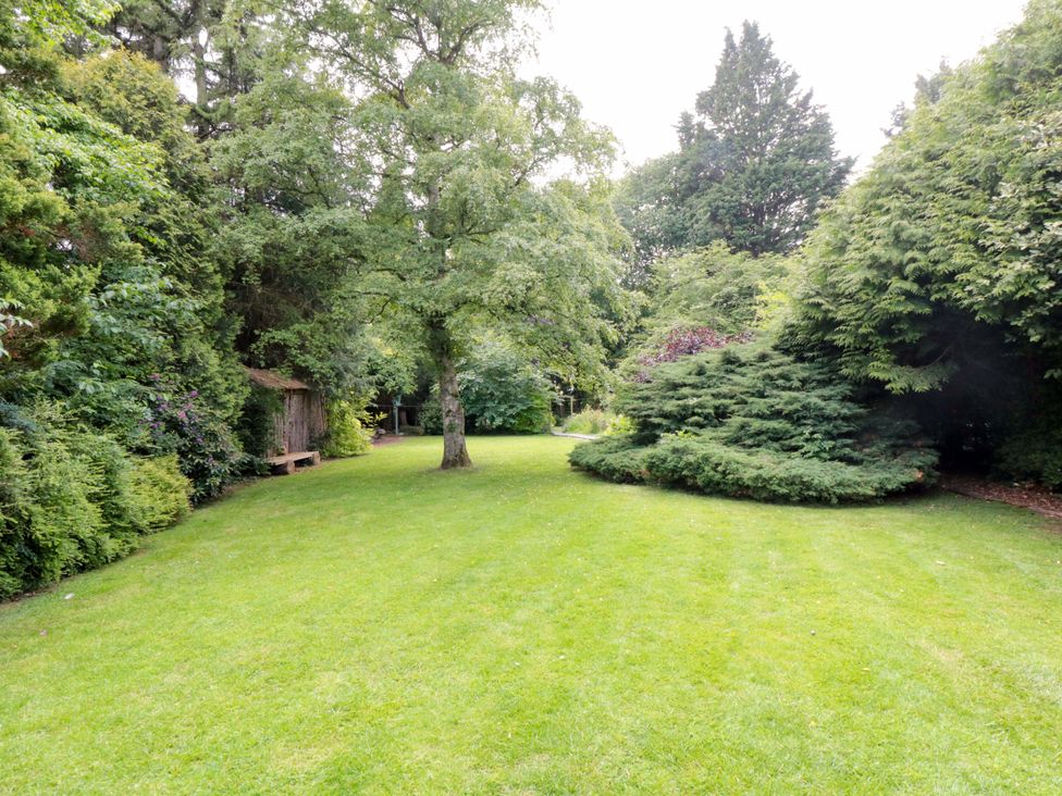 A garden with grass, trees and a wooden structure at Lawnswood