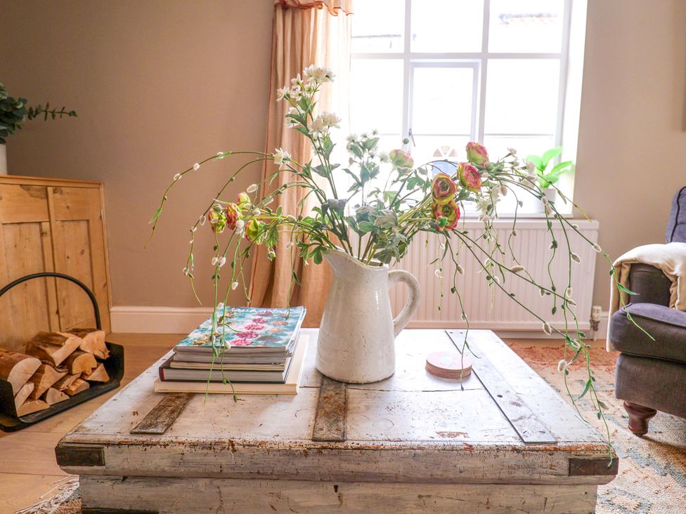 A living room with a coffee table displaying flowers and books at 11 Ballygate in Babbacombe