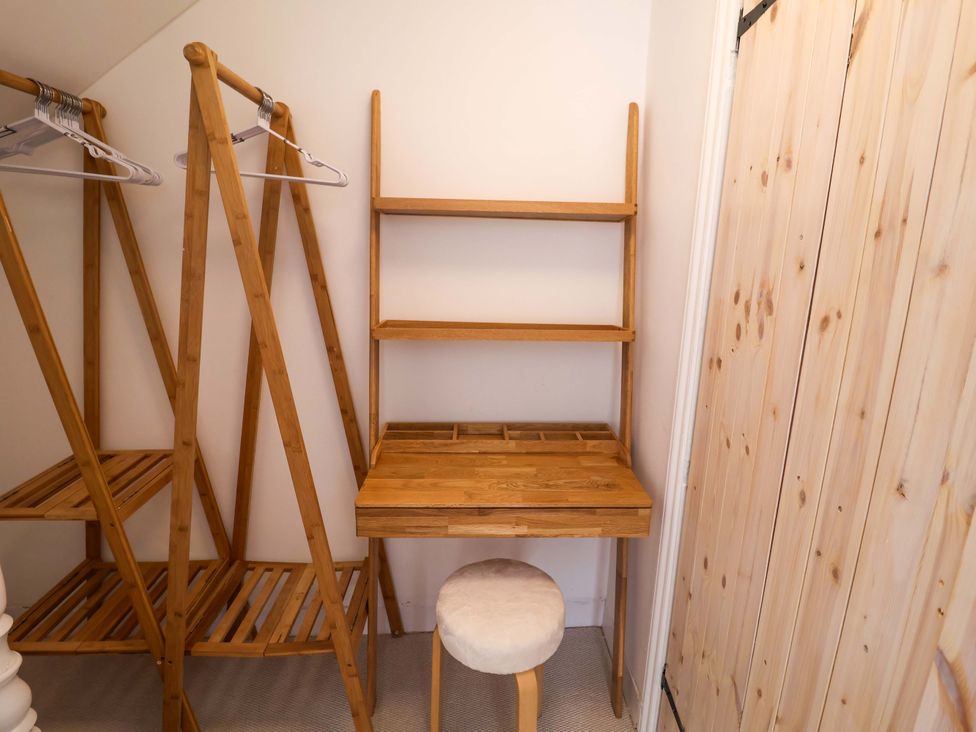 A closet with a clothes rack, shelf, desk, and stool at 11 Ballygate in Babbacombe