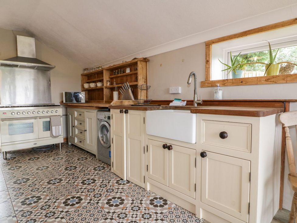 A kitchen with cabinets and appliances at Sunset Cottage in Gorran Churchtown