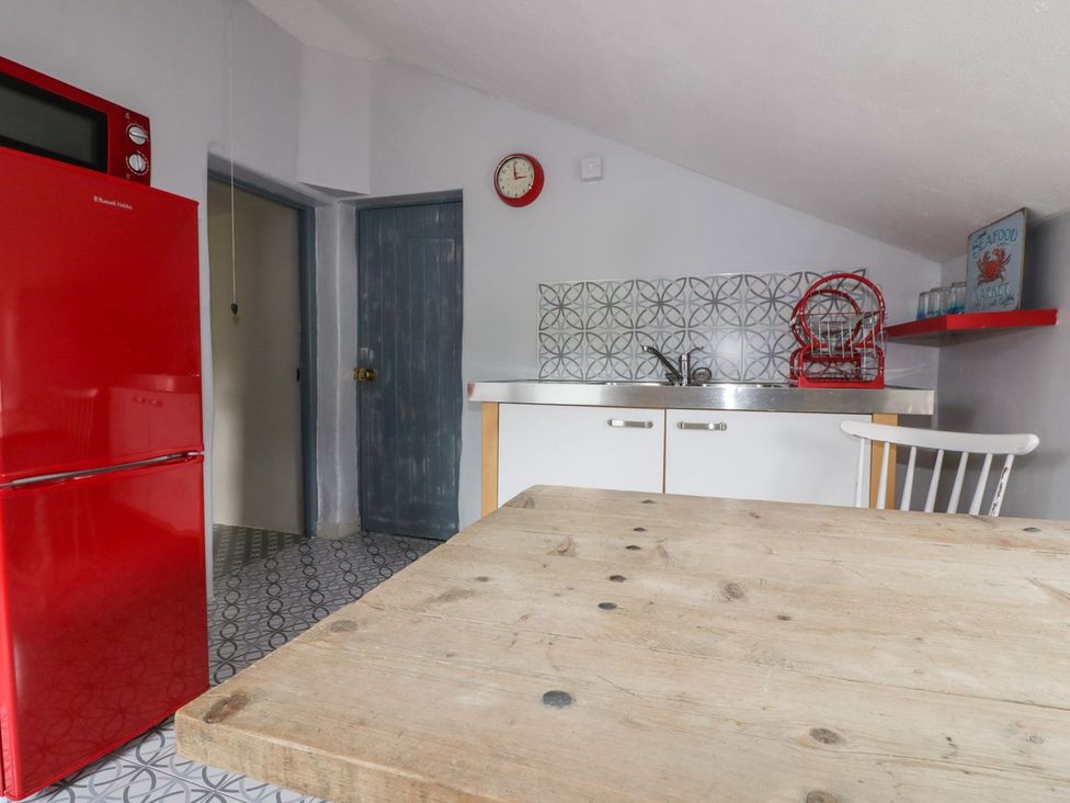 A kitchen with a red refrigerator and sink at Sunset Cottage in Gorran Churchtown