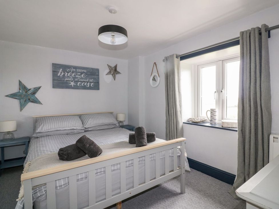 A bedroom with a bed and window at Sunset Cottage in Gorran Churchtown