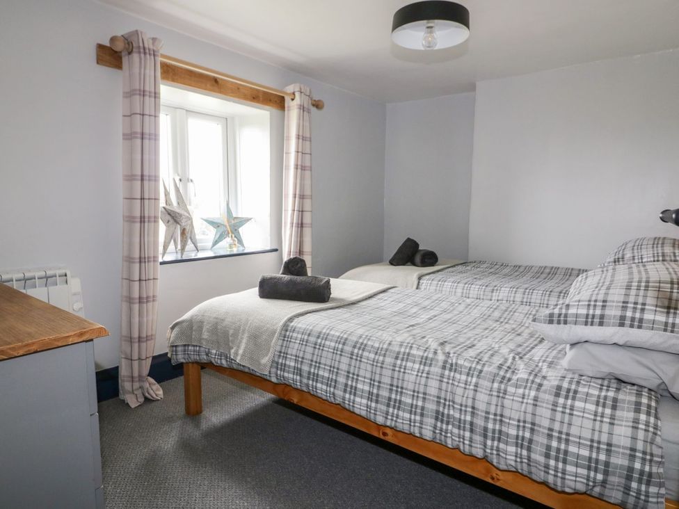 A bedroom with two beds and a window at Sunset Cottage in Gorran Churchtown
