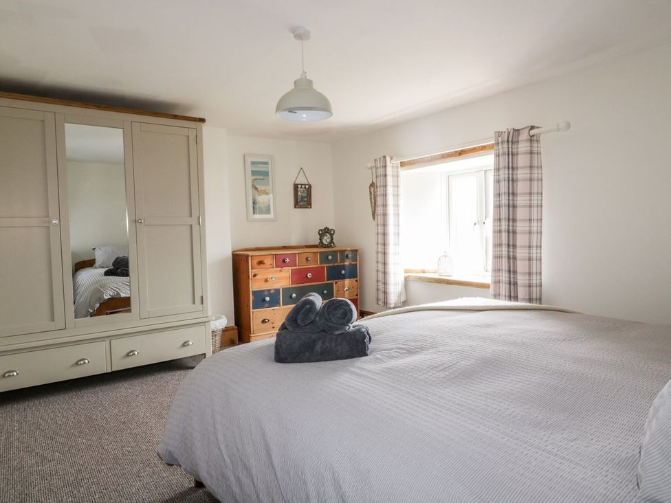 A bedroom with a bed and a wardrobe at Sunset Cottage in Gorran Churchtown