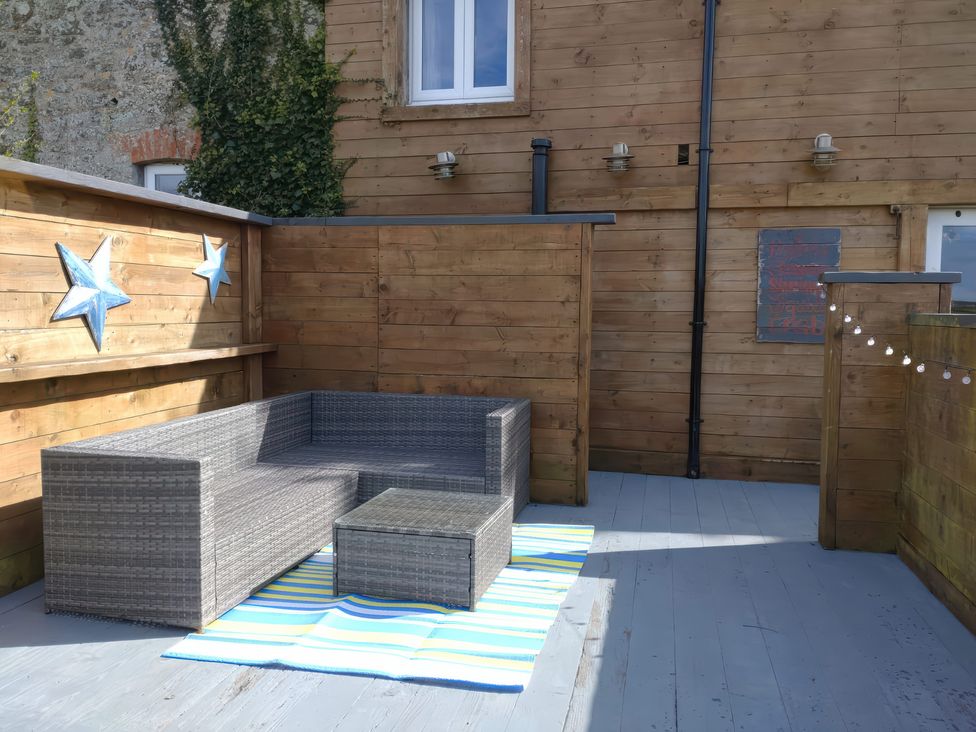 An outdoor seating area with a sofa and coffee table at Sunset Cottage in Gorran Churchtown