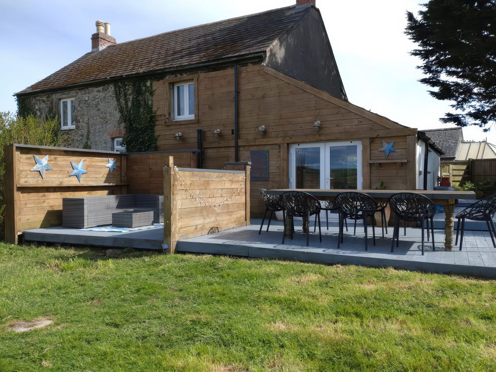 A garden with wooden decking and outdoor furniture at Sunset Cottage in Gorran Churchtown
