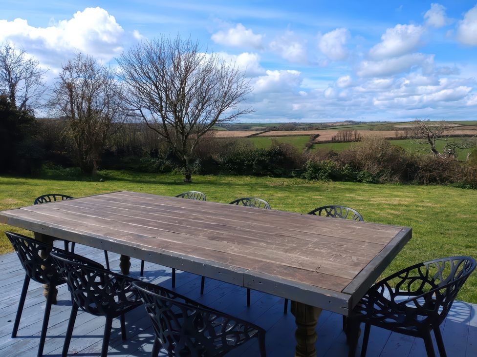 A dining table with chairs on the lawn at Sunset Cottage in Gorran Churchtown