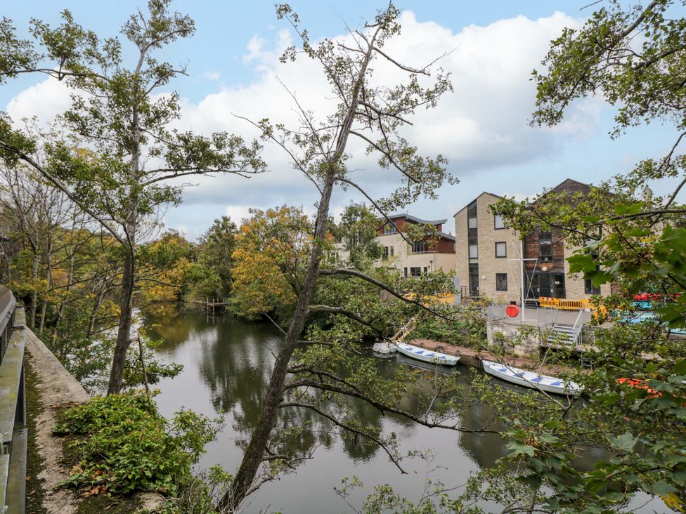 A view of water with boats and buildings among trees at 3 The Stoneyard Bath