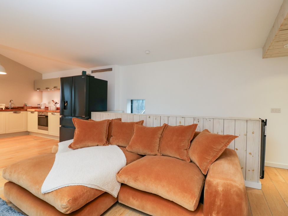 A living room with a sofa and kitchen area at 3 The Stoneyard Bath