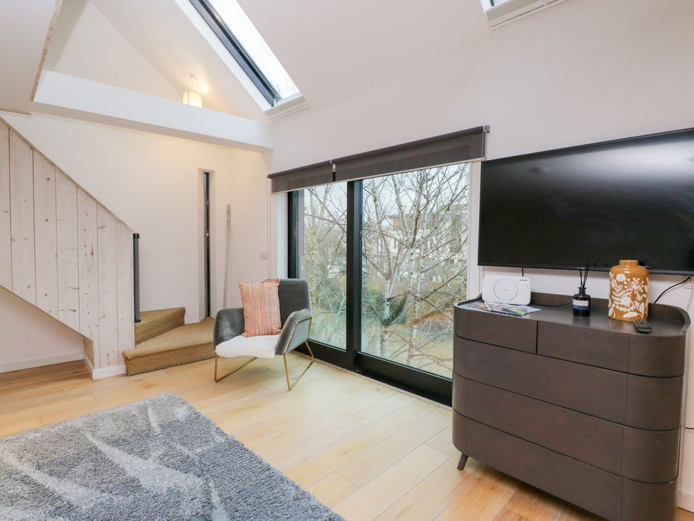 A living room with a television and a staircase at 3 The Stoneyard, Bath
